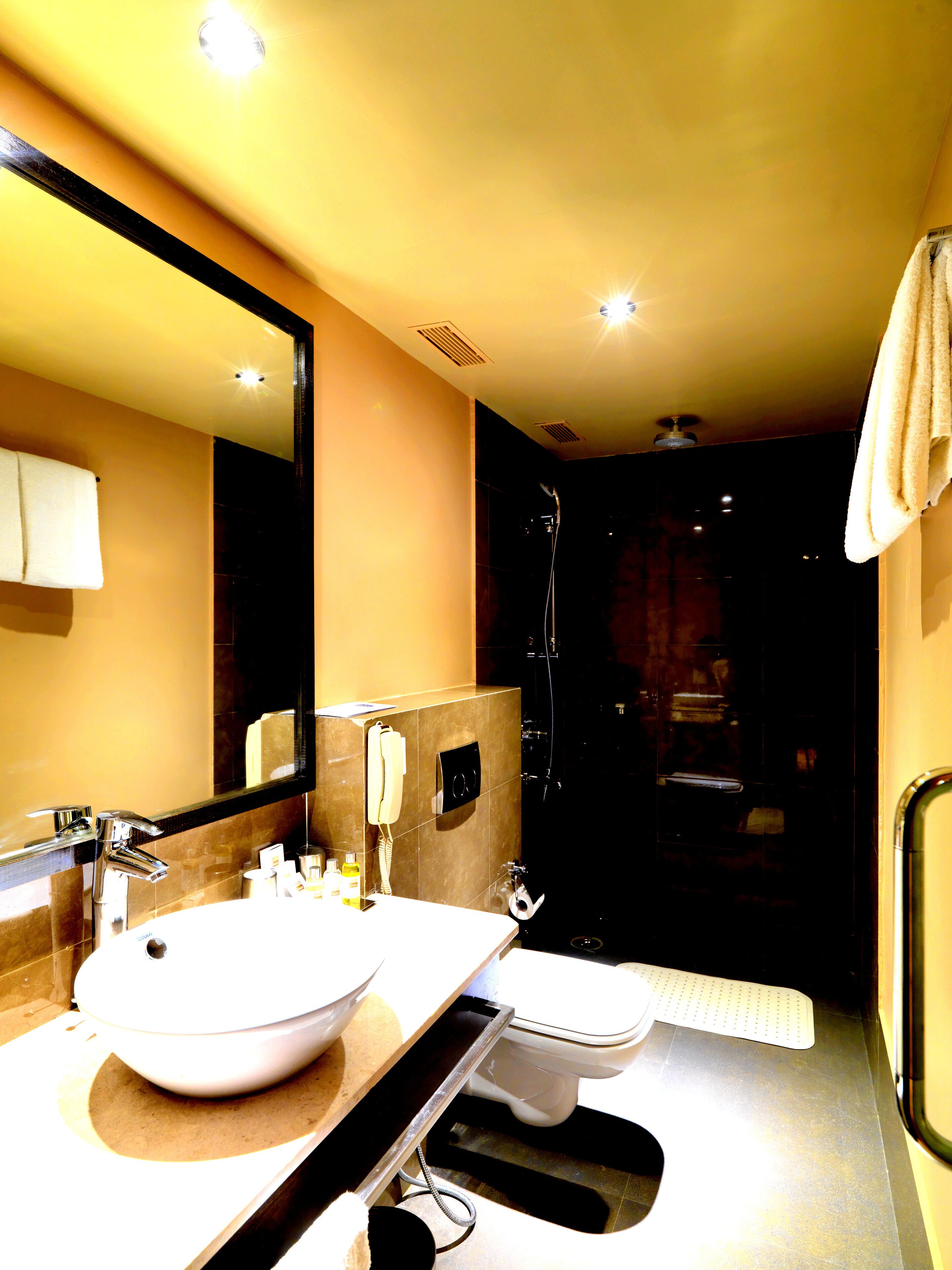 Een moderne badkamer met een grote spiegel, twee wasbakken, een toilet en een douche.