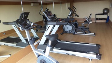 A gym with multiple treadmills, stationary bikes, and a rack of dumbbells.
