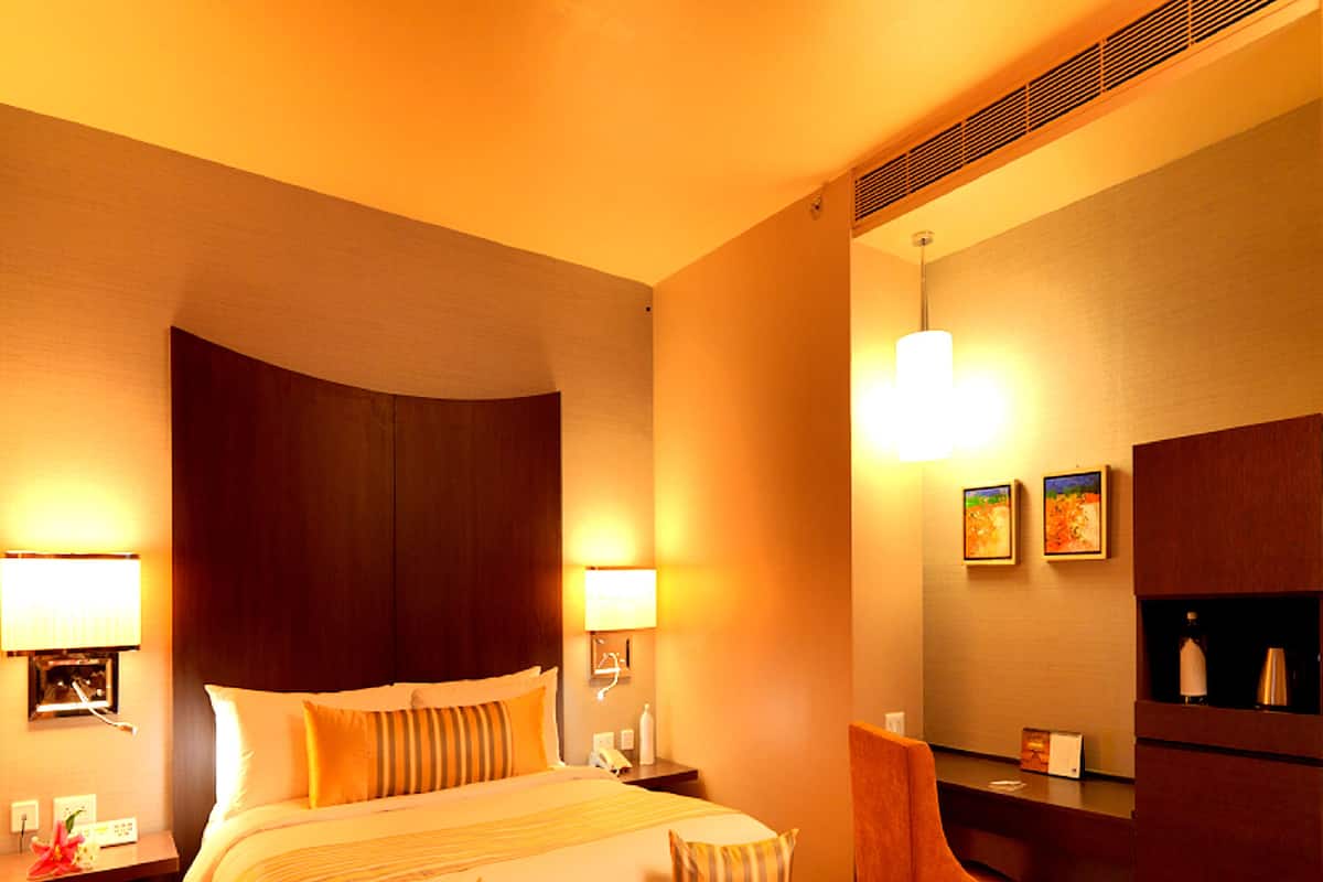 A hotel room with a large bed, bedside lamps, a desk, a chair, and a coffee table with flowers.