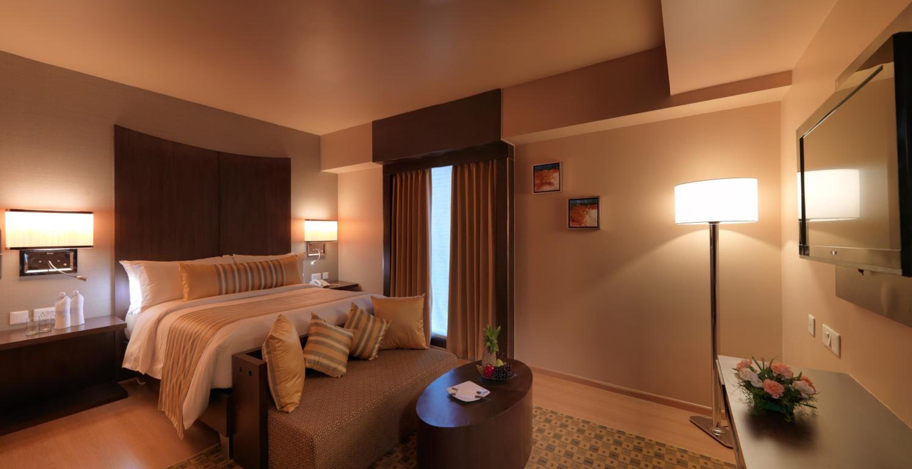 A hotel room with a large bed, bedside tables, a desk, and a mirror.