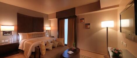 A hotel room with a large bed, bedside tables, a desk, and a mirror.