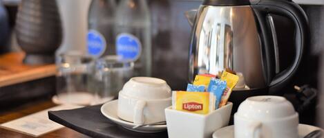 A coffee station with two cups, a teapot, and Lipton tea packets.