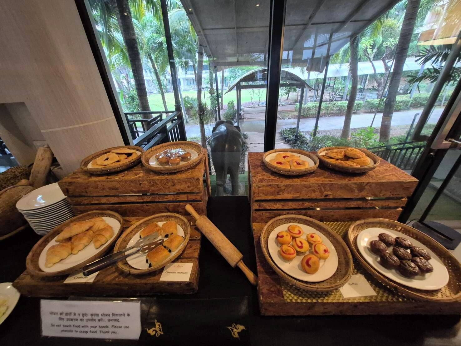 Un bufé con diversos productos horneados y un letrero que indica comer con las manos.
