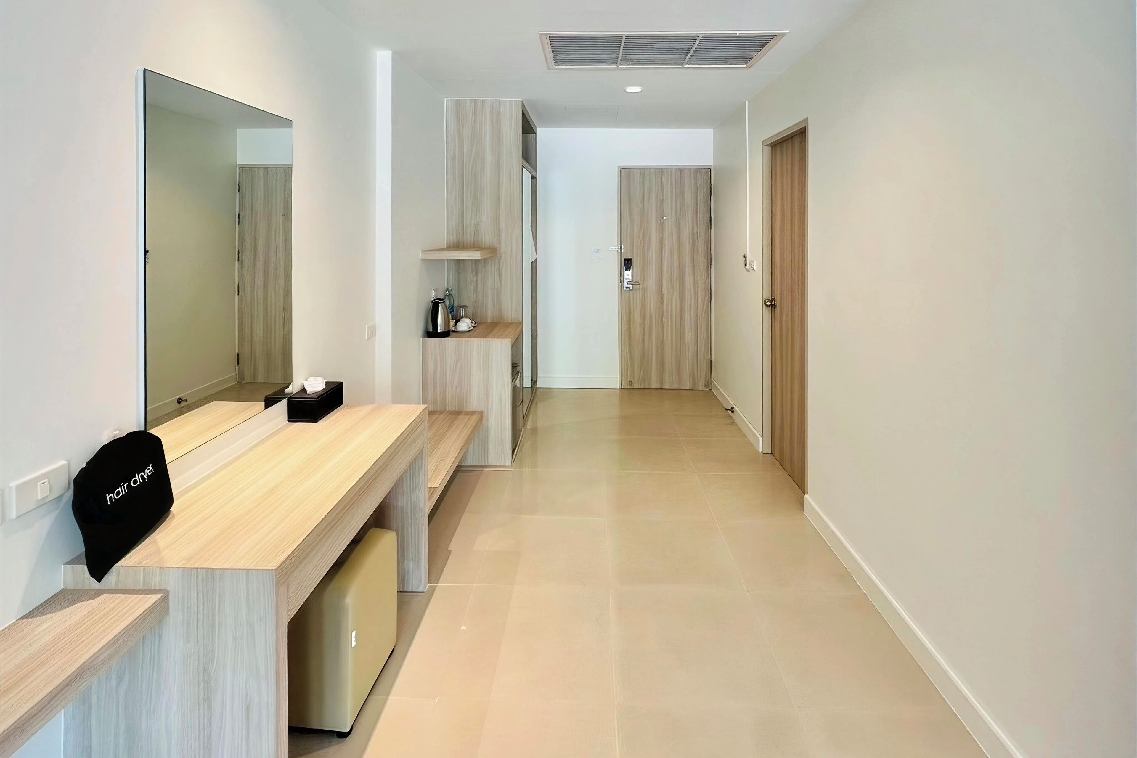 A modern hotel corridor with a wooden reception desk, a mirror, and a bench.
