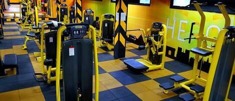 Un gimnasio con diferentes máquinas de ejercicio, un mostrador de recepción y una zona de atención al cliente.