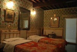 Una habitación con dos camas, un espejo y una mesita.
