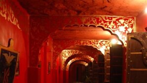A corridor with red walls, black and white checkered flooring, and ornate ceiling decorations. - Hotel Bhairon Vilas (Bikaner)