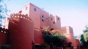A pink building with a central courtyard, a fountain, and a sign indicating a restaurant. - Hotel Bhairon Vilas (Bikaner)