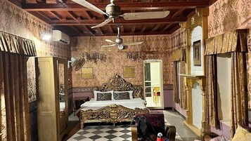 Una habitación con cama, armario, ventilador de techo y papel tapiz estampado.