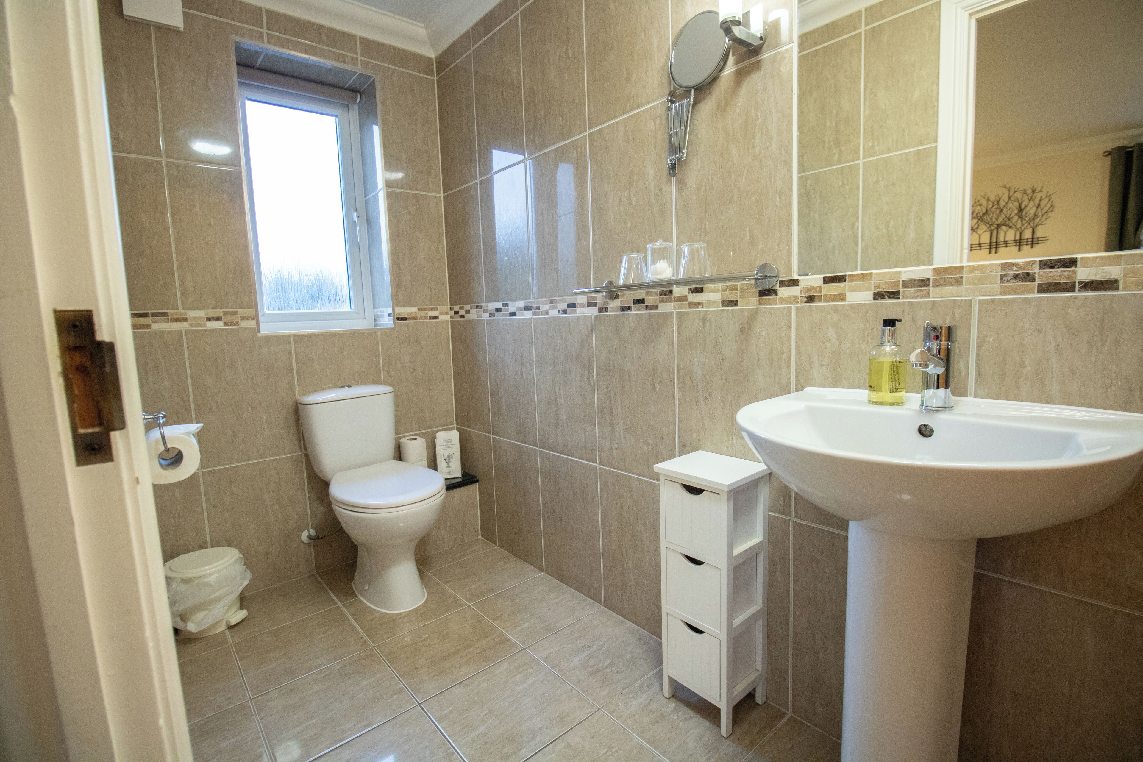 A bathroom with a toilet, sink, and a window.