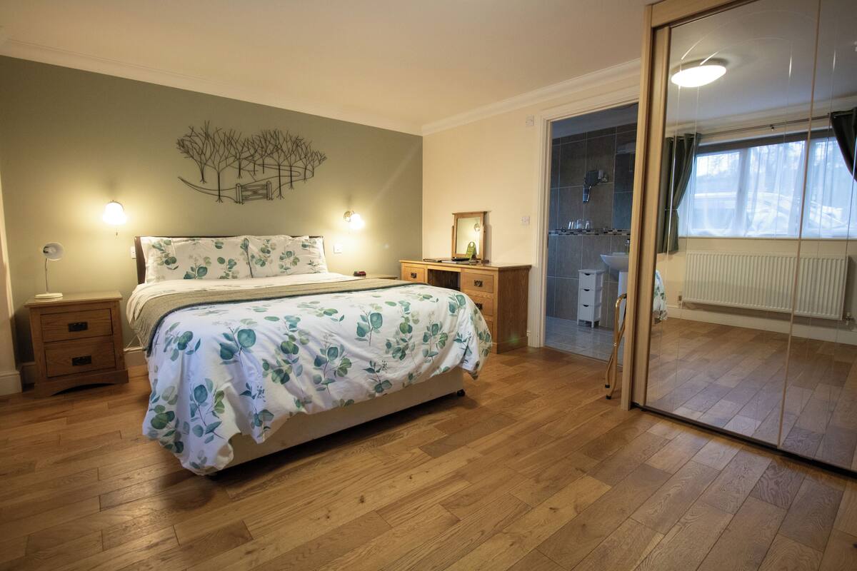 Une chambre à coucher avec un lit, des tables de chevet, un miroir et une vue sur la salle de bain.