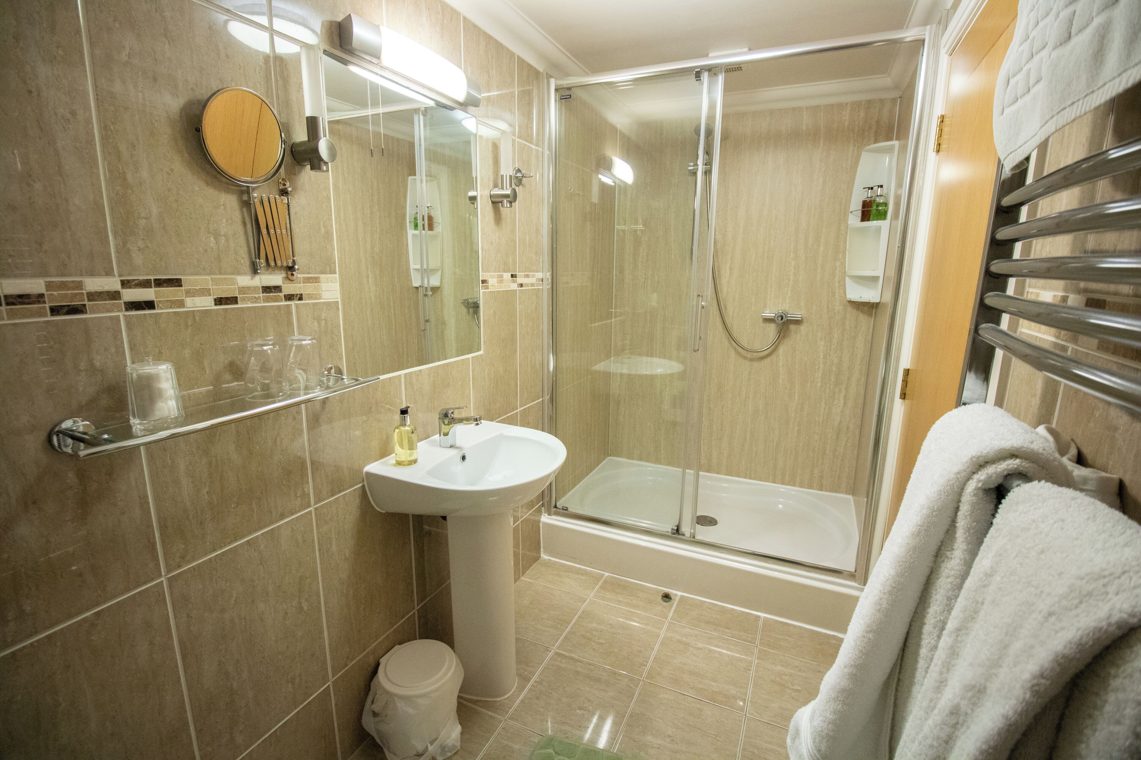 A bathroom with a glass-enclosed shower, a sink, and a mirror.