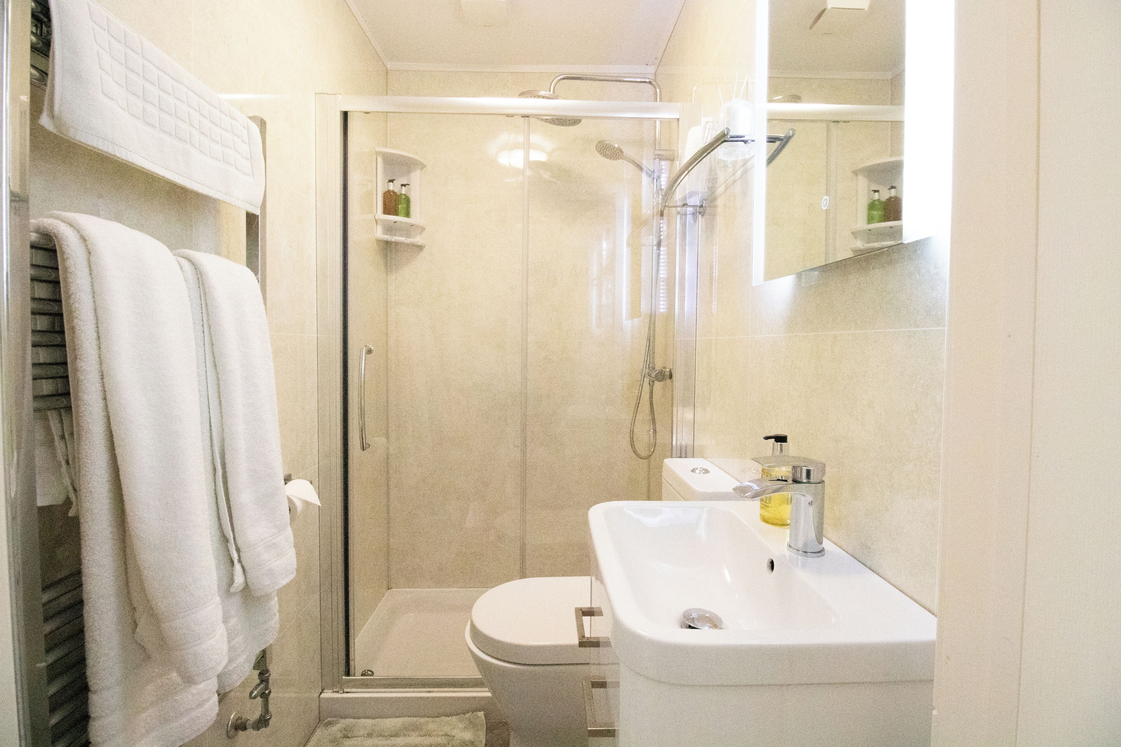 Un baño moderno con ducha envuelta en vidrio, lavabo blanco y retrete.