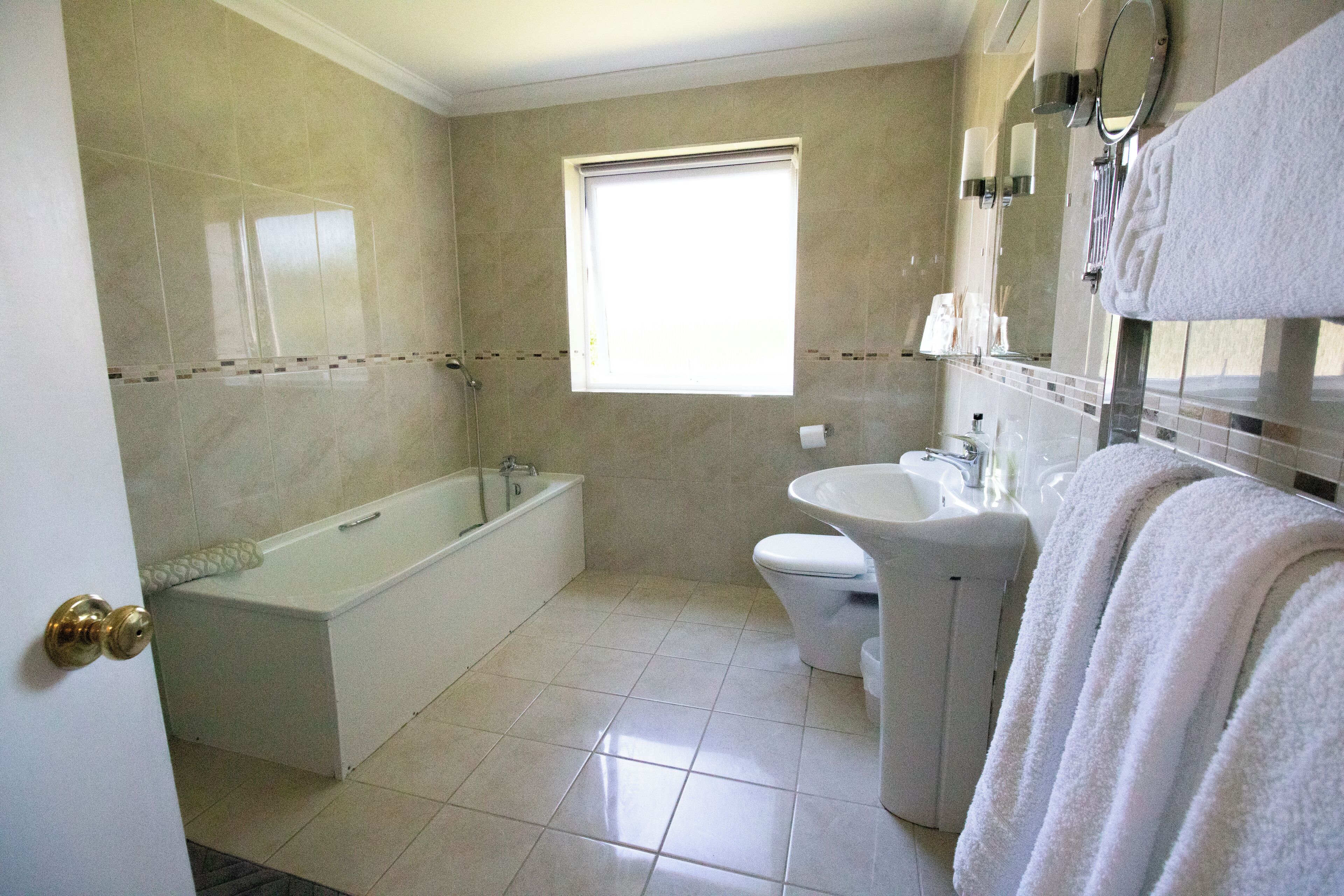 Un baño con bañera, inodoro, lavabo y ventana que proporciona luz natural.