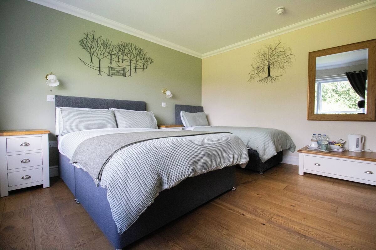 Une chambre à coucher comprenant un lit, des tables de chevet, une commode et des œuvres d’art murales.