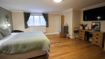 A bedroom with a bed, a desk, a chair, a television, and a radiator.