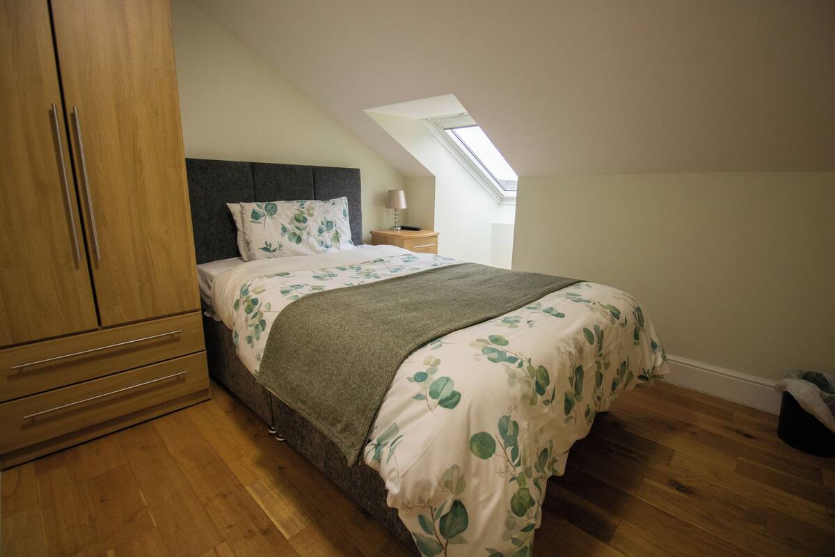 Une chambre à coucher avec un lit, une armoire en bois et un puits de lumière.
