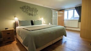 Een slaapkamer met een bed, nachtkastjes, wanddecoratie en een raam met gordijnen.