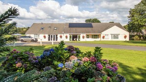 Een gebouw met een schuin dak, zonnepanelen en een overdekte ingang.