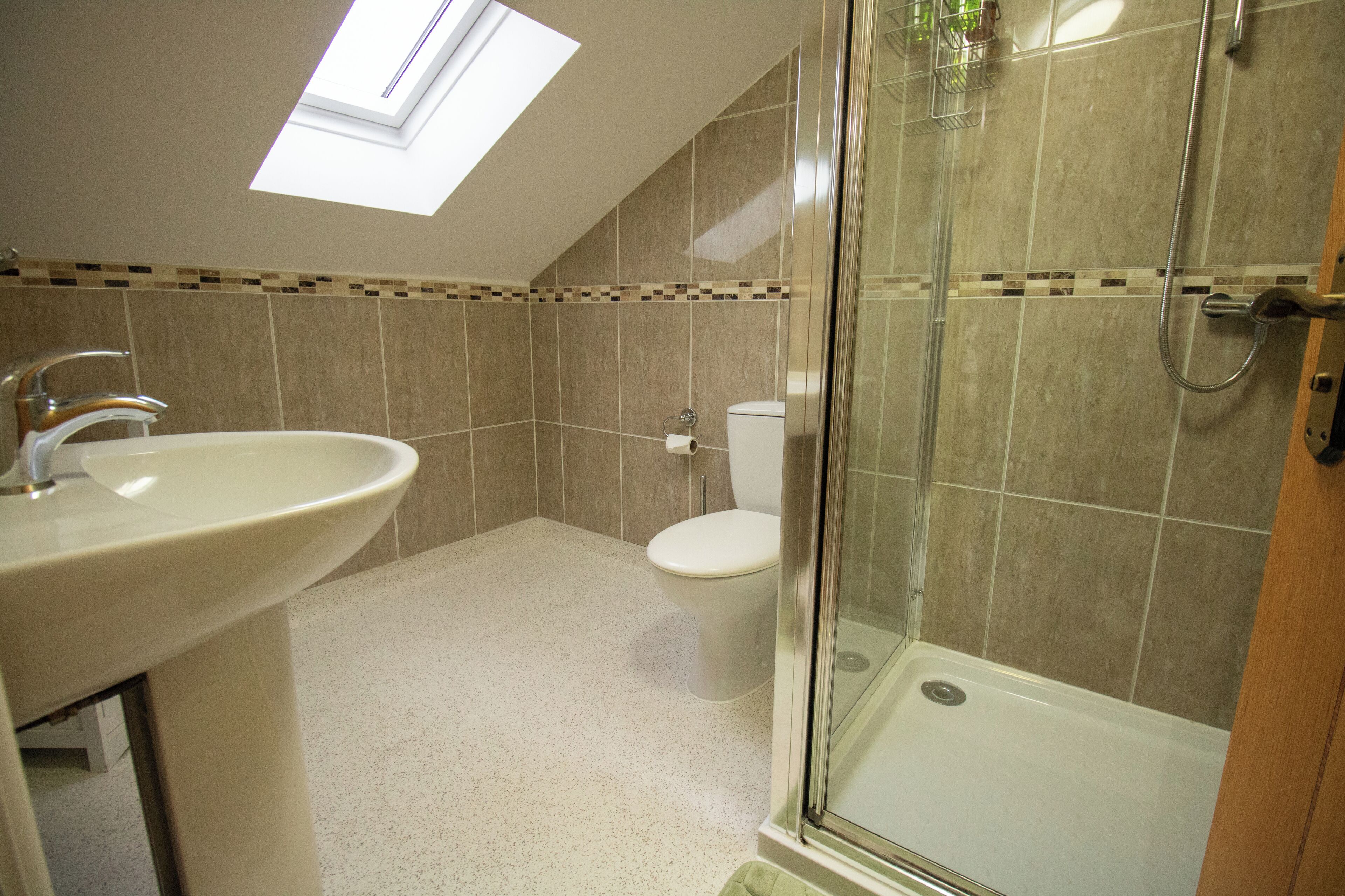 Ein Badezimmer mit Oberlicht, einer Dusche und einem WC.