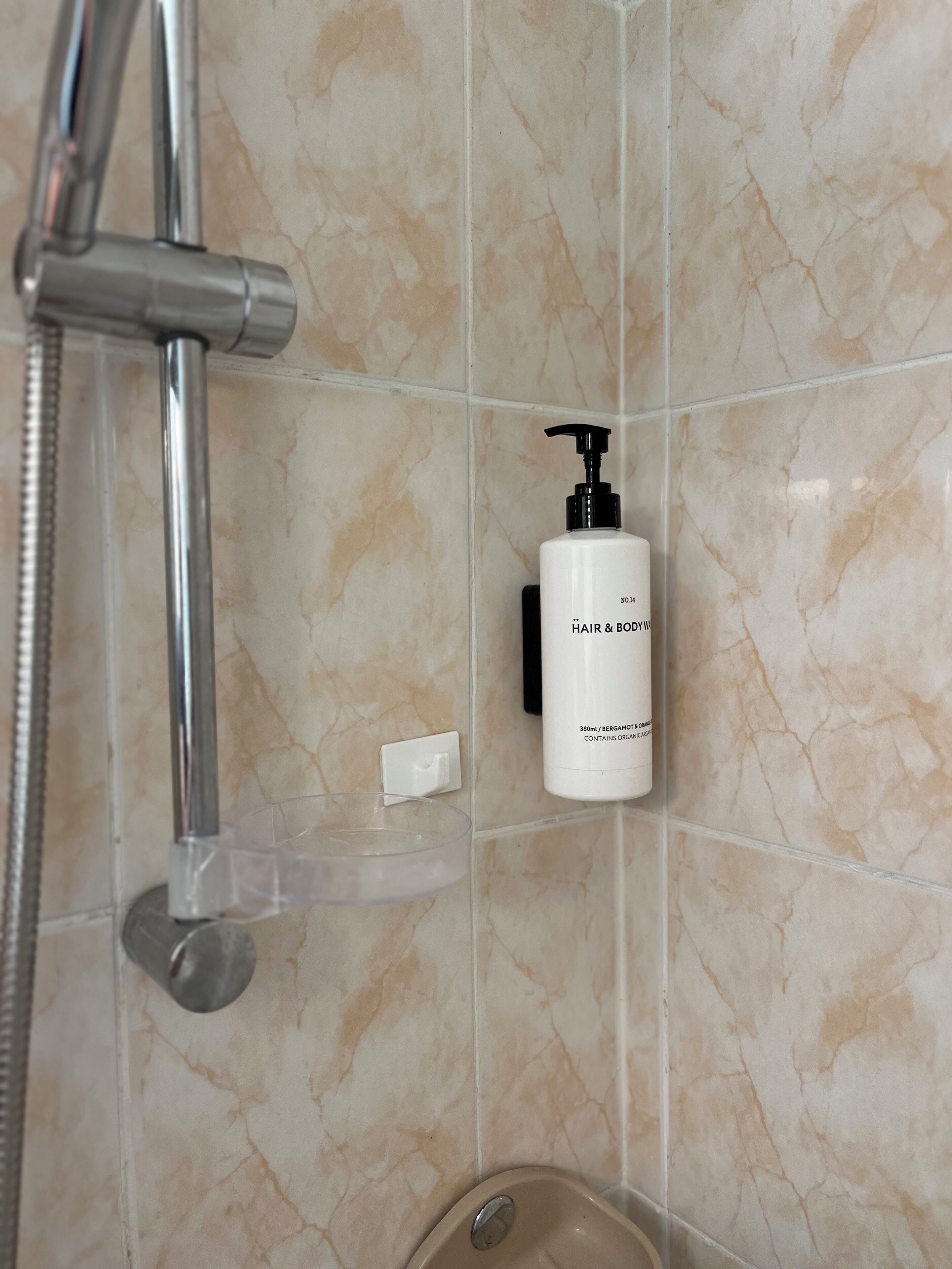 A bathroom with a shower, a bottle of hair and body wash, and a soap dish.