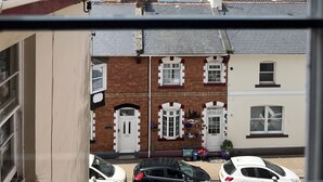 A view from a window overlooking a street with parked cars and a bridge in the distance. - Lynton House (Teignmouth)