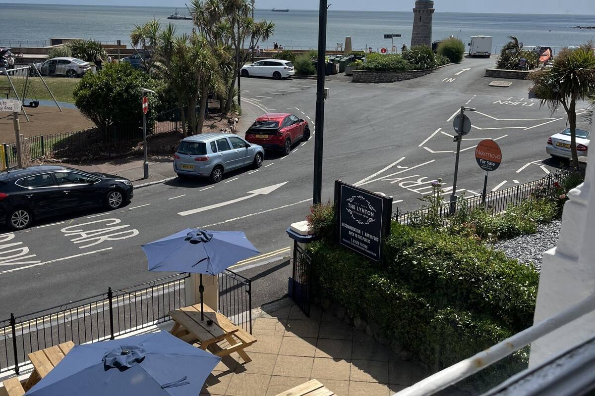 A coastal view with a parking area, a lighthouse, and outdoor seating.