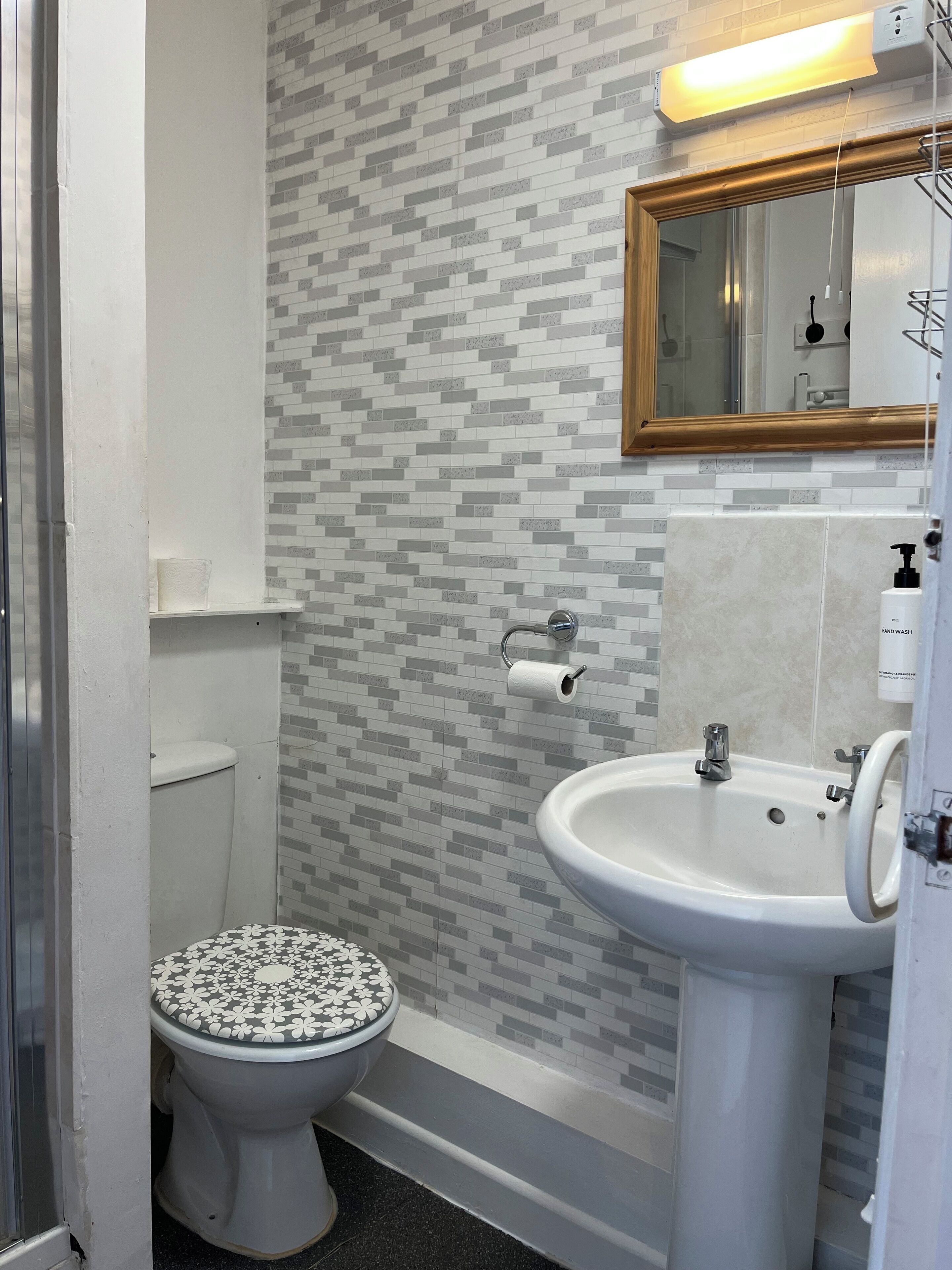 A bathroom with a toilet, sink, and mirror.
