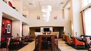 A spacious dining area with a high ceiling, multiple dining tables, and chairs. - Hampton Inn & Suites Minot Airport (Minot)
