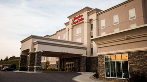 A hotel with a modern facade, a clear sign reading "Hampton Inn & Suites," and a covered entrance with a 12-foot clearance. - Hampton Inn & Suites Minot Airport (Minot)