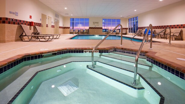 An indoor swimming pool with a tiled edge, a lifeguard station, and lounge chairs. - Hampton Inn & Suites Minot Airport (Minot)