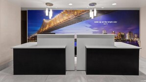 A reception area with two counters, a large cityscape mural, and a slogan on the wall. - La Quinta Inn & Suites by Wyndham Boutte (Boutte)