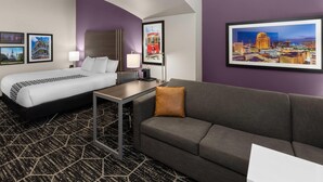 A hotel room with a bed, a sofa, a desk, and framed pictures on the walls. - La Quinta Inn & Suites by Wyndham Boutte (Boutte)