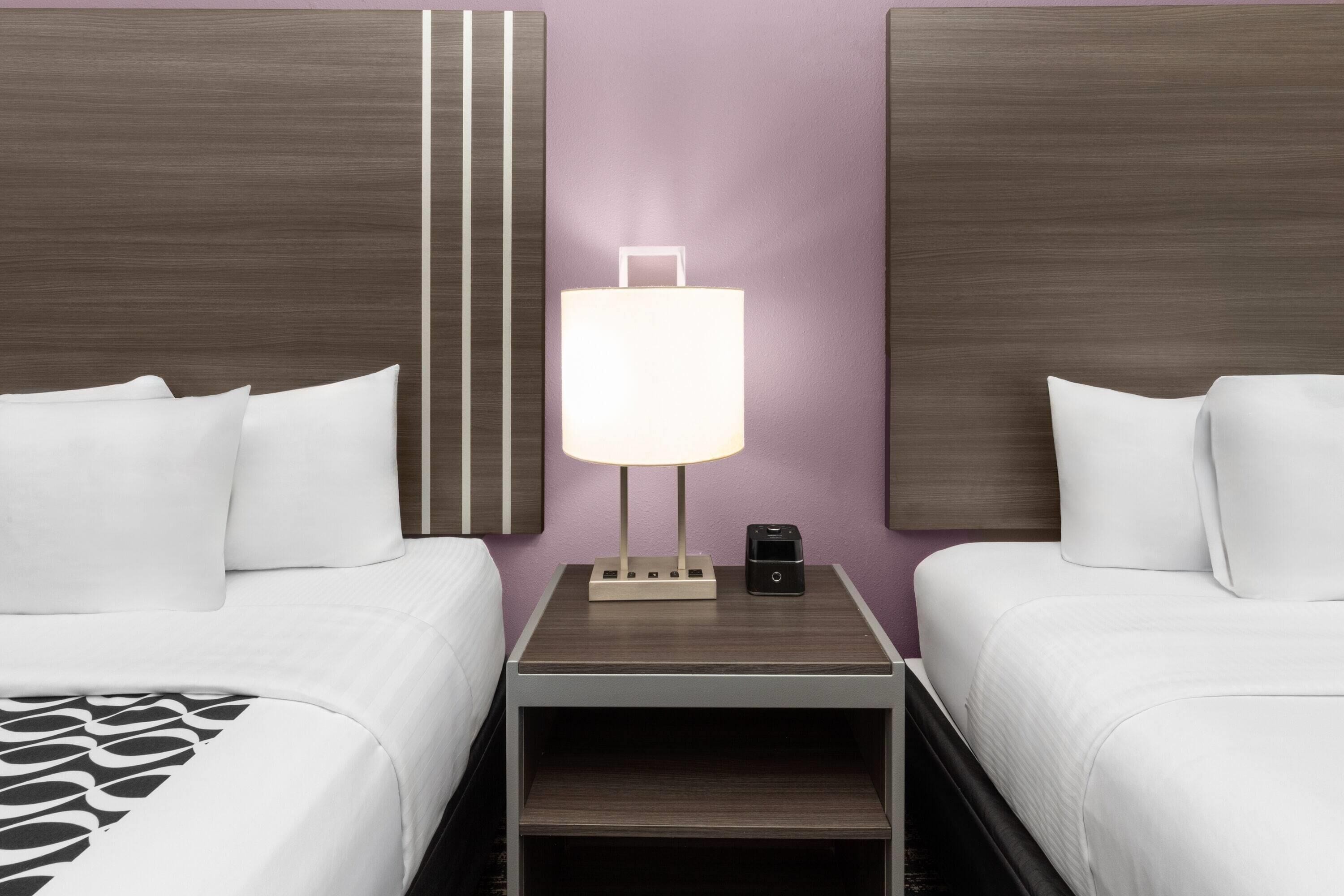 Une chambre d’hôtel avec deux lits, une table de chevet avec une lampe et une petite enceinte.