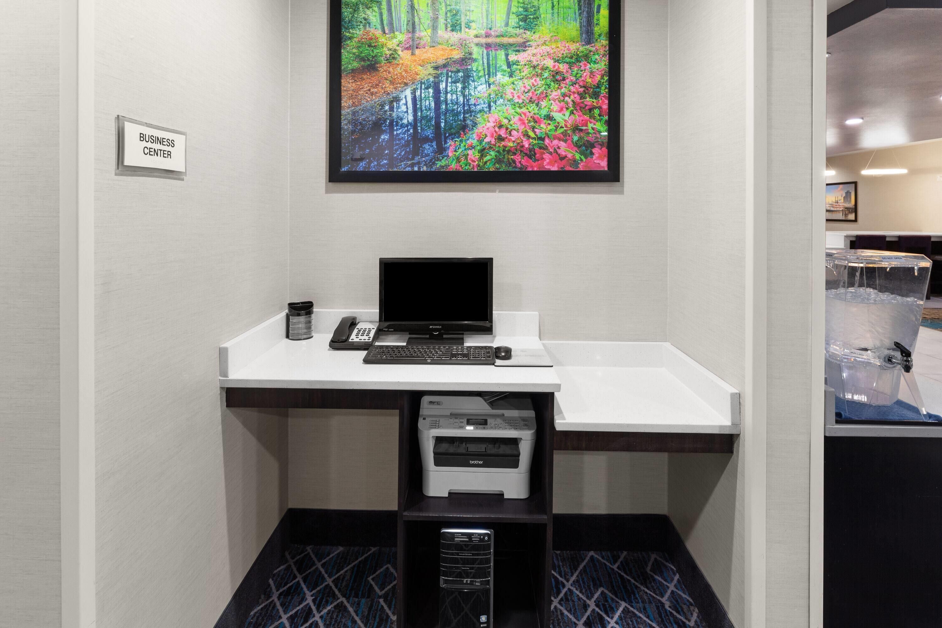 A business center desk with a computer, phone, and printer.