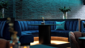 Un área de estar moderna con un sofá azul, una mesa central y un jarrón decorativo.