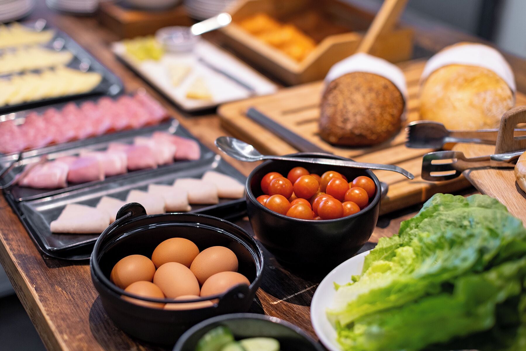 Buffet com diversos alimentos, incluindo ovos, tomates e carne.