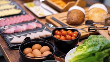 Buffet com diversos alimentos, incluindo ovos, tomates e carne.