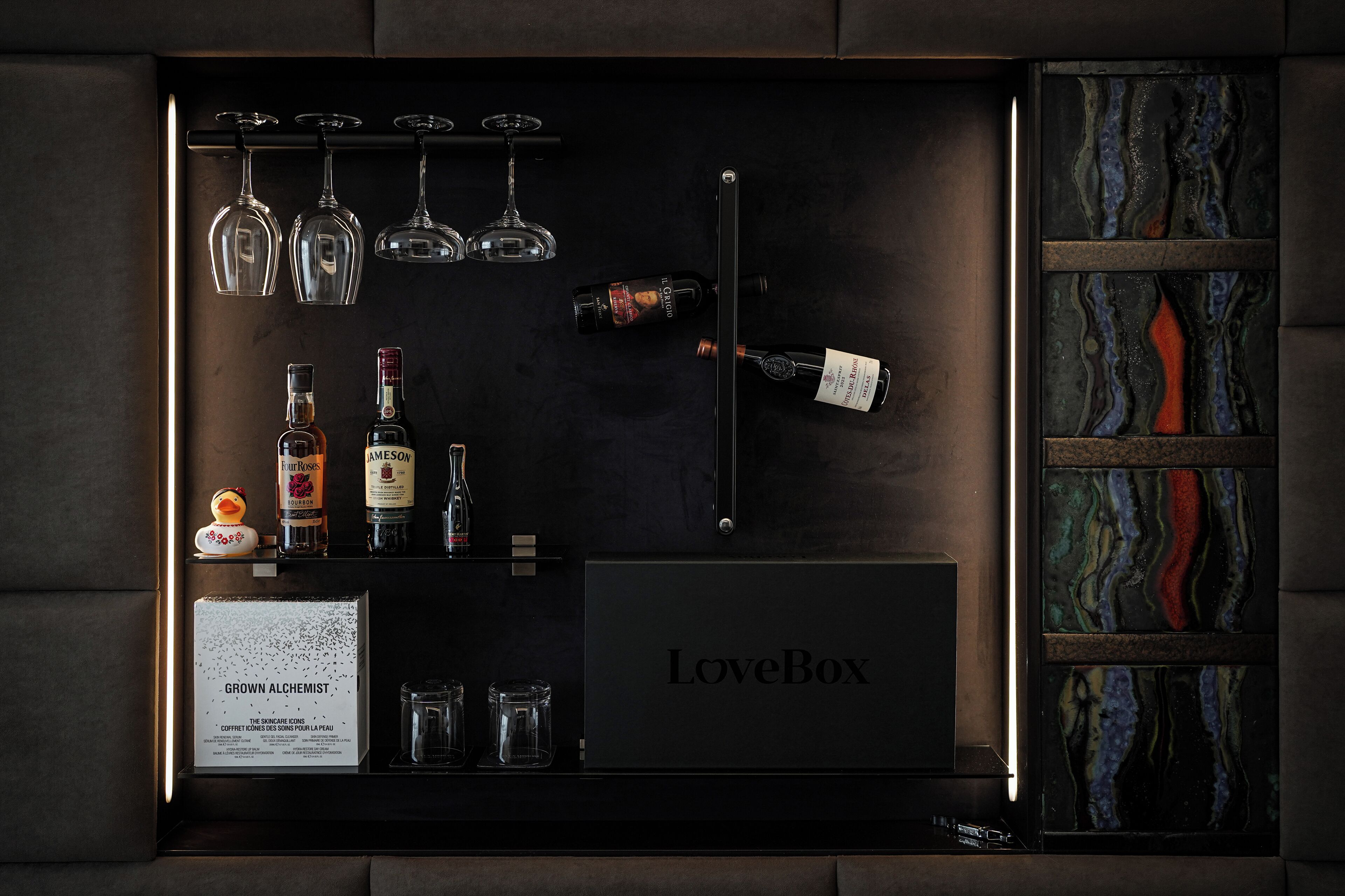 Un mini-bar bien organisé, contenant diverses bouteilles, des verres et un menu encadré.