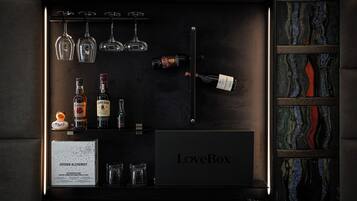 Un mini-bar bien organisé, contenant diverses bouteilles, des verres et un menu encadré.