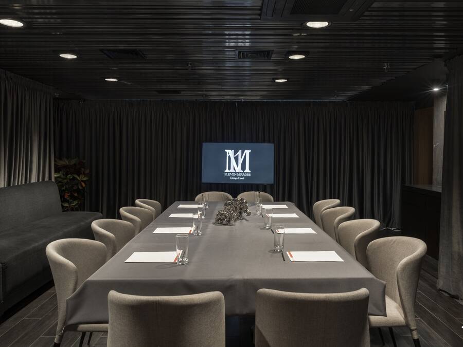 Une salle de conférence avec une longue table, des chaises, un canapé et un écran affichant le logo.