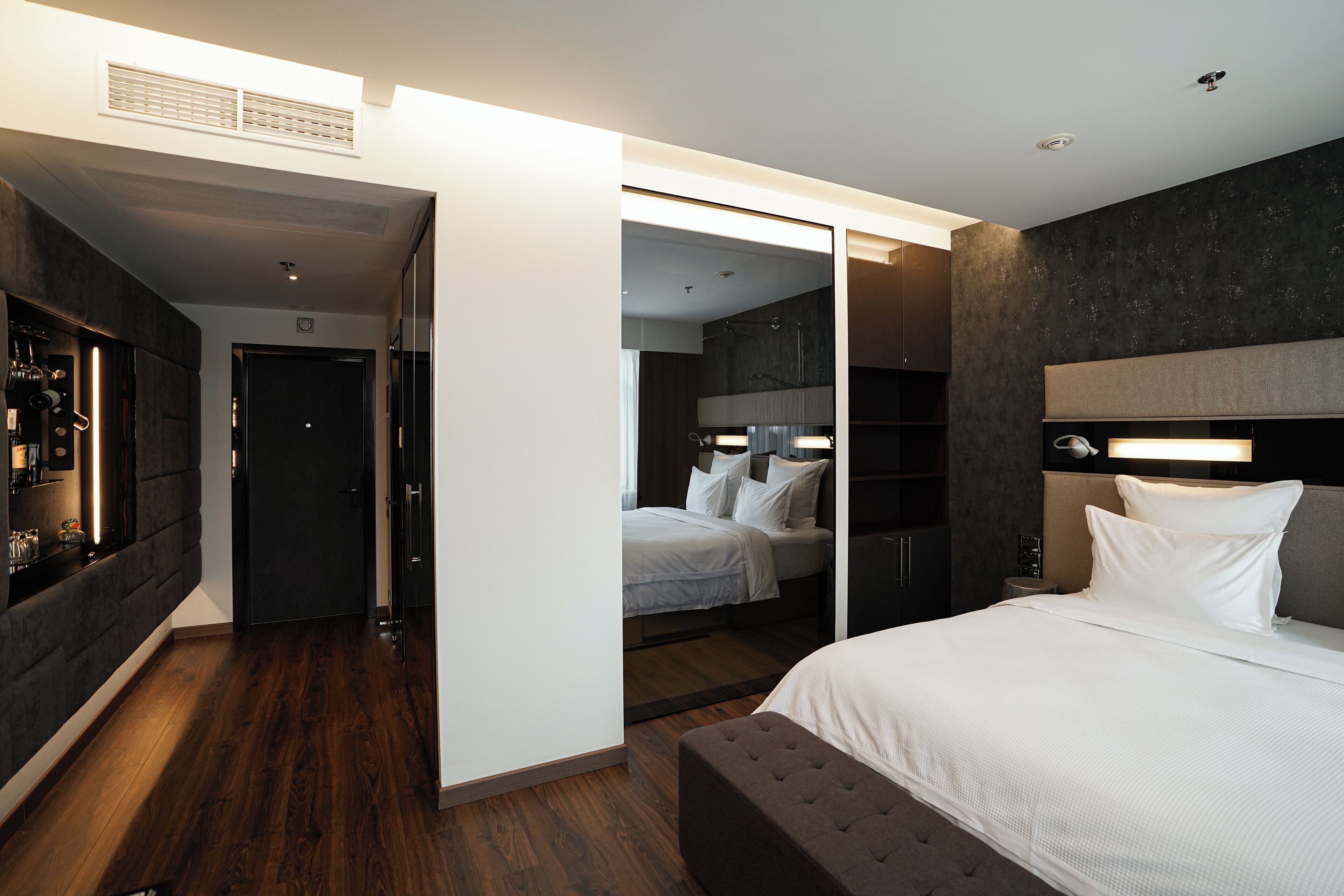 A modern hotel room with a large bed, a walk-in closet, and a separate bathroom.