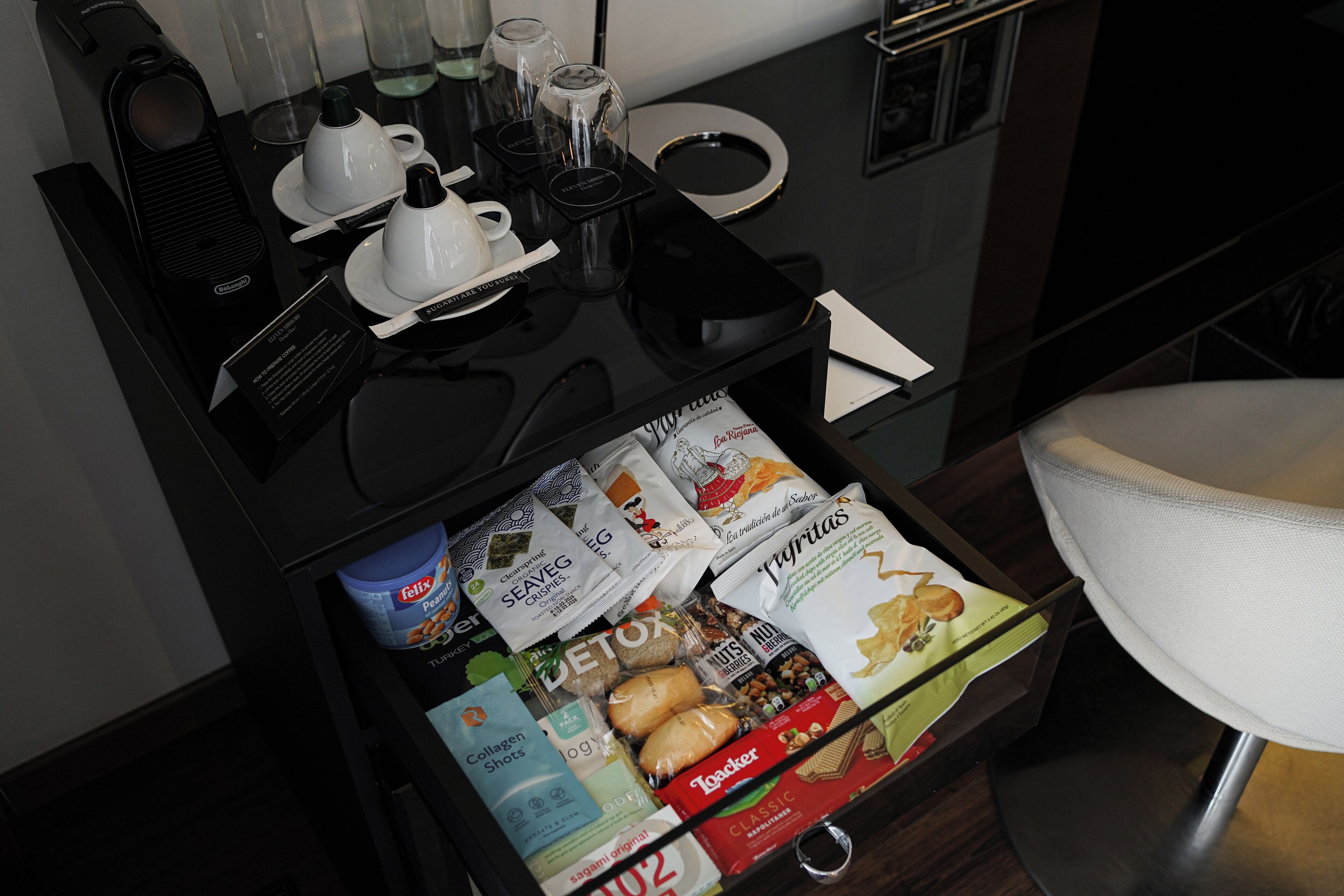 Habitación de hotel con minibar que contiene una cafetera, vasos y una bandeja con productos para el desayuno.