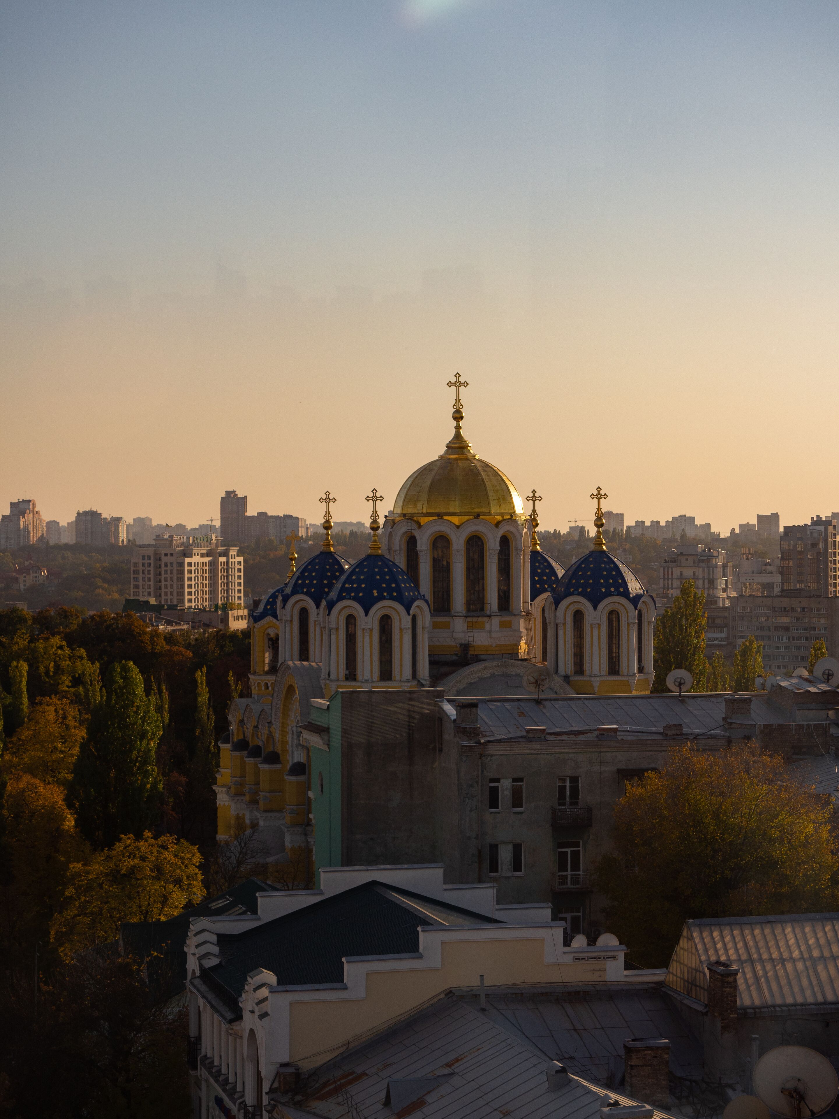 A large church with multiple domes and a golden dome, surrounded by urban buildings and trees.