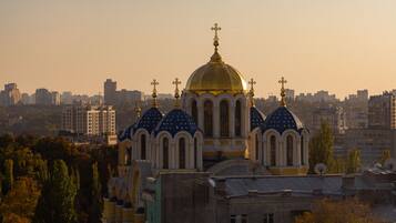 A large church with multiple domes and a golden dome, surrounded by urban buildings and trees.