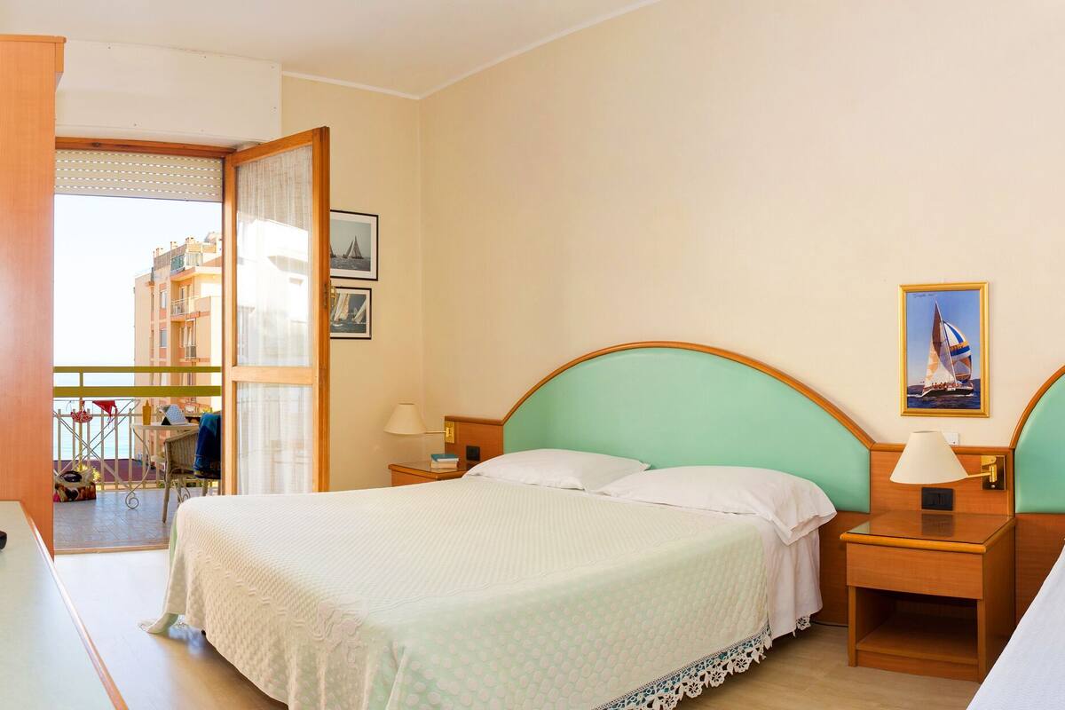 Une chambre d’hôtel avec deux lits, une télévision, un vase de fleurs et une vue sur le balcon extérieur.