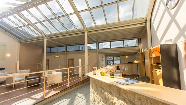 Amplio espacio interior con techo alto, una recepción, zona de estar y vistas a través de un techo de cristal.
