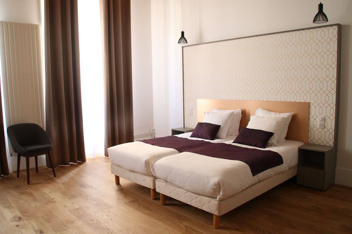 Una cama doble con cabecera de madera, dos mesitas de noche y una silla.