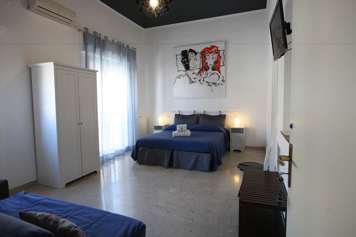 Une chambre à coucher avec un lit, une armoire, un tableau et un téléviseur fixé au mur.