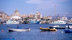 A harbor with various boats docked, a prominent domed building, and a crane in the background. - B&B La Casa di Paola (Trapani)